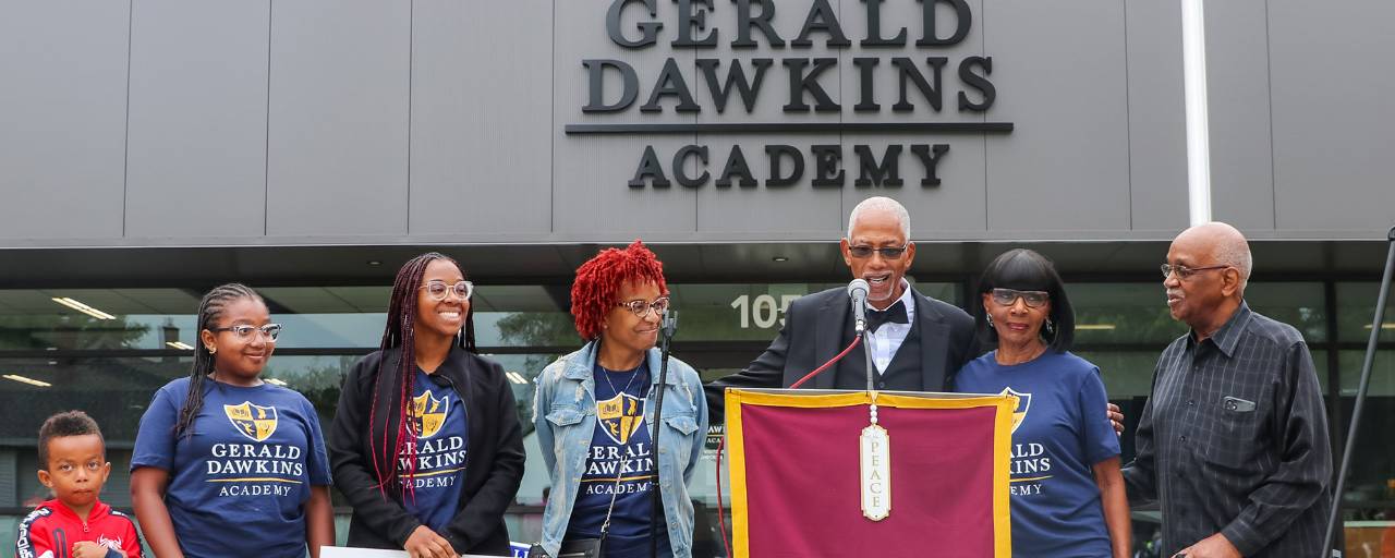 Family members of Gerald Dawkins gather in front of the school named after Gerald on its ribbon-cutting ceremony.